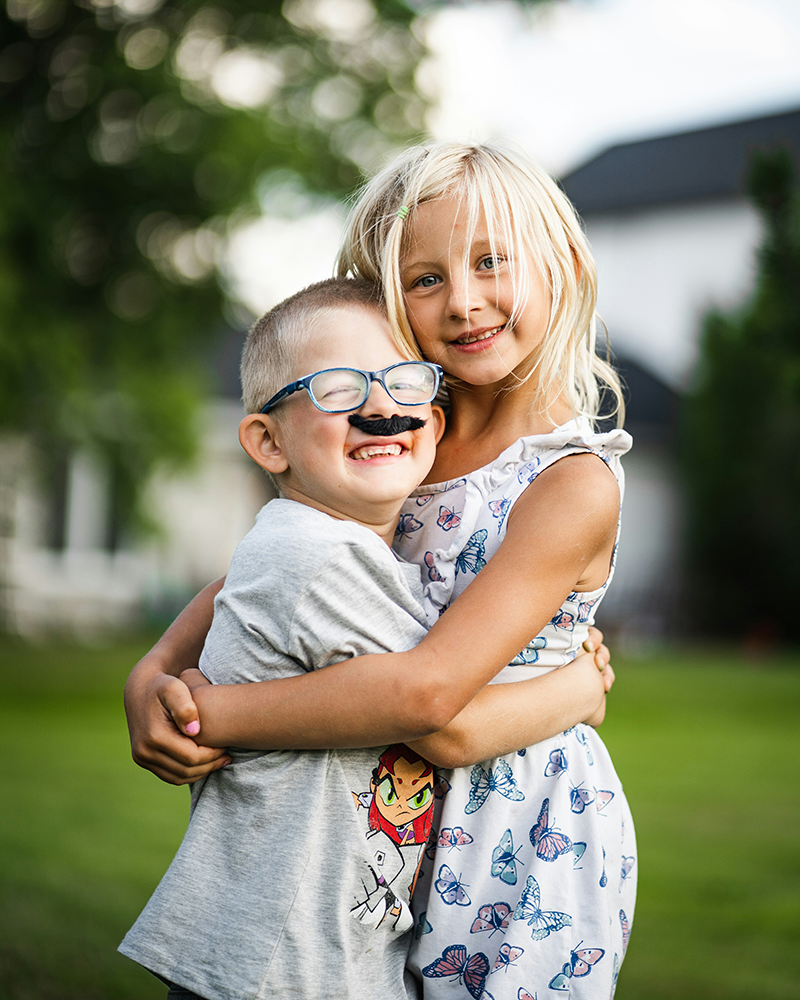 Young siblings hugging each other.