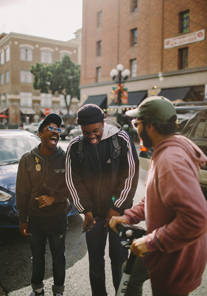 Friends hanging out by some cars.